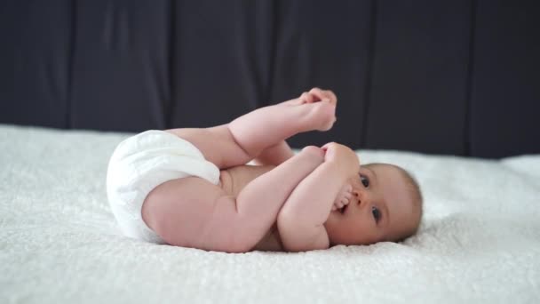 Bebê Menina Deitado Branco Folha Segurando Sua Legst — Vídeo de Stock