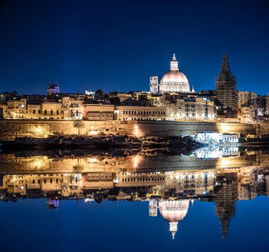 Valletta eski kasabasının gece limanında denizdeki yansımasıyla aydınlandı. İyi geceler Valletta. Şehir merkezi.