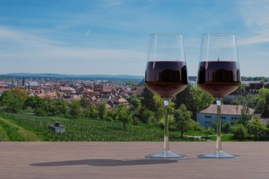 Tarlaların panoramik manzarasında iki kırmızı şarap kadehi ve tarihi Bamberg kasabası, Almanya