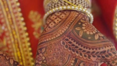 Beautiful video of an Indian bride in traditional wedding attire as per Hindu custom, wearing colorful bangles in her hands decorated with henna mehndi sitting with folded hands in her marriage