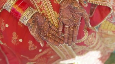 Beautiful video of an Indian bride in traditional wedding attire as per Hindu custom, wearing colorful bangles in her hands decorated with henna mehndi sitting with folded hands in her marriage