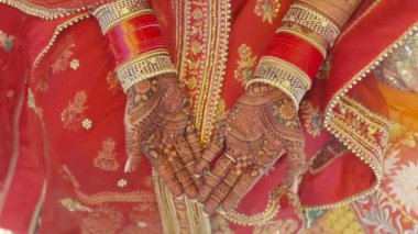 Beautiful video of an Indian bride in traditional wedding attire as per Hindu custom, wearing colorful bangles in her hands decorated with henna mehndi sitting with folded hands in her marriage
