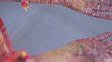 Beautiful video of an Indian bride in traditional wedding attire as per Hindu custom, wearing colorful bangles in her hands decorated with henna mehndi sitting with folded hands in her marriage