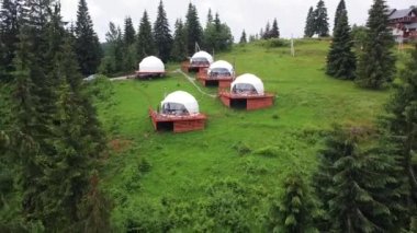 glamping in summer, many domed houses against the backdrop of mountains. house with a transparent window in the garden. Tented camp of elite rest. White bubble in a mountains
