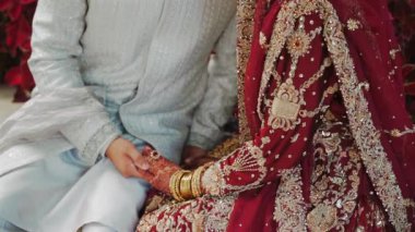 Groom tying cultural sacred thread on brides hand at a traditional Indian wedding. Indian wedding ritual. Shot of a beautiful Indian Bride entering in her wedding