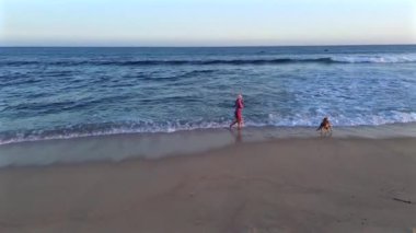 Beyaz kumsalın olduğu çarpıcı bir sahil. Bir kız yanında oyuncu köpeği ile balık tutmaya çalışıyor. Güneş ışıl ışıl parlıyor, plaj eğlencesi ve rahatlığı için mükemmel bir gün yaratıyor..