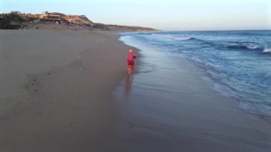 Beyaz kumsalın olduğu çarpıcı bir sahil. Bir kız yanında oyuncu köpeği ile balık tutmaya çalışıyor. Güneş ışıl ışıl parlıyor, plaj eğlencesi ve rahatlığı için mükemmel bir gün yaratıyor..