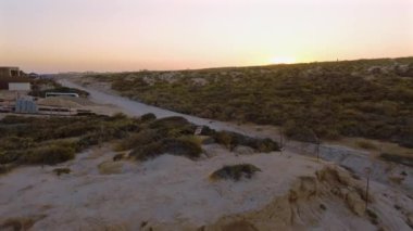 Beyaz bir kamyonet, San Lucas, Meksika kıyısındaki lüks evlerin yanındaki toprak yolda ilerliyor. Çarpıcı okyanus manzarası ve güzel mimari huzurlu bir sahil macerası yaratır..