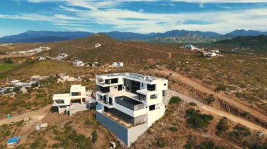 Zarif şemsiye ve sandalyelerin palmiye ağaçlarıyla çevrili olduğu tropikal bir tatil köyünde lüks havuz manzarası. Sakin atmosfer çarpıcı bir günbatımı ile güçlenir, Meksika, Cabo San Lucas 08.10.2024