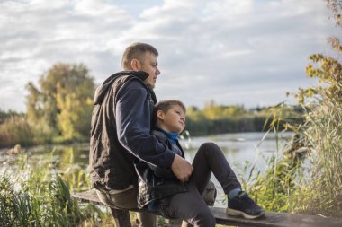 Baba dışarıda, bankta oğluna sarılıyor. Baba ve oğul arasındaki değerli anlar.