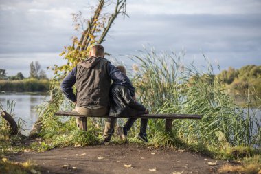 Baba dışarıda, bankta oğluna sarılıyor. Baba ve oğul arasındaki değerli anlar.
