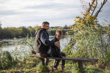 Baba dışarıda, bankta oğluna sarılıyor. Baba ve oğul arasındaki değerli anlar.