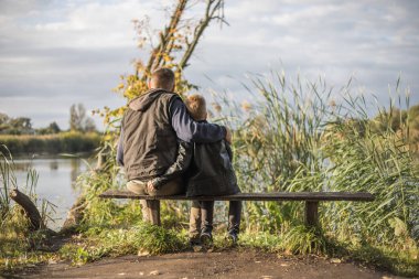 Baba dışarıda, bankta oğluna sarılıyor. Baba ve oğul arasındaki değerli anlar.