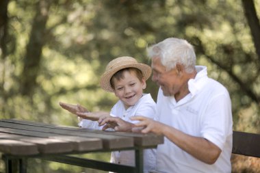 Happy senior man Grandfather with cute little boy grandson playing in forest clipart