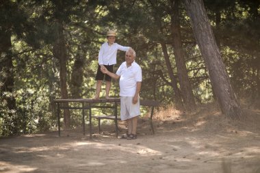 Mutlu son sınıf öğrencisi, büyükbabası ve küçük tatlı torunu ormanda oynuyorlar.
