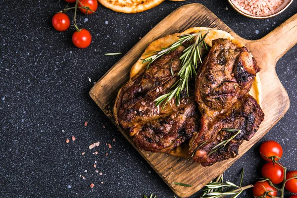 stock image Steaks. Sliced grilled meat steak New York or Ribeye with spices rosemary and pepper on black  board. Top view.