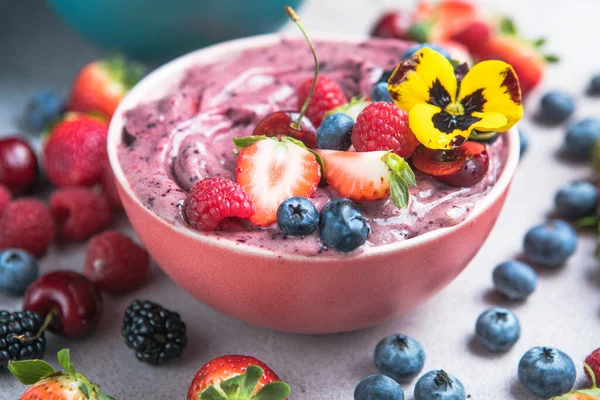 stock image Two summer acai smoothie bowls with strawberries, blueberries,   on gray concrete background. Breakfast bowl with fruit and cereal, close-up, top view, healthy food