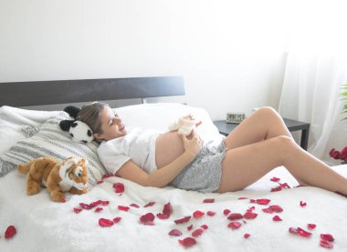 Hamile bir kadın yatakta kucağında oturuyor. Hamilelik, annelik ve doğum öncesi bakım kavramı. Annem yeni bir hayata başladı..