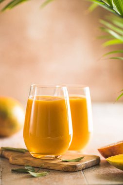 İki mango lassi ya da bardakta kesar süt. Hint sağIıklı ve mangolu soğuk bir içecek. Taze Lassi yoğurttan, sudan, baharatlardan, meyvelerden ve buzdan yapılır..