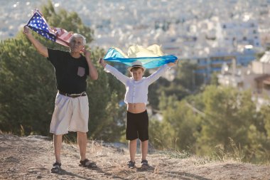 Emekli adam ve çocuk, ABD ve Ukrayna 'nın bayraklarını şehir görüşünde tutuyorlar.