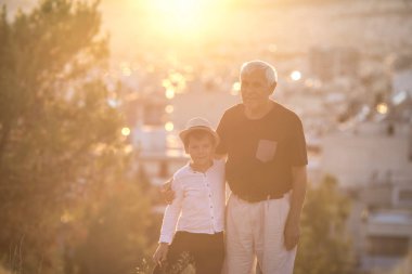 Büyükbaba ve torun dışarıda eğleniyor, gülümsüyor ve sarılıyorlar. Arkadaş canlısı aile kavramı.