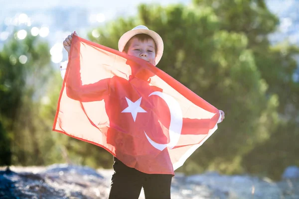 Boy holding Turkey flag against city.  Kid hand waving Turkish flag view from back, copy space for text