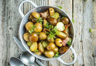 Yavru patatesler, pastırma, maydanoz ahşap bir arka planda kızartma tavasında, yakın plan