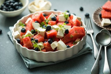 Karpuzlu yaz salatası, beyaz peynir ve gri arka planda yabanmersini. Vegan, Avrupa yemekleri.