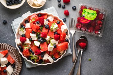 Karpuzlu yaz salatası, beyaz peynir ve gri arka planda yabanmersini. Vegan, Avrupa yemekleri.