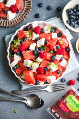 Karpuzlu yaz salatası, beyaz peynir ve gri arka planda yabanmersini. Vegan, Avrupa yemekleri.