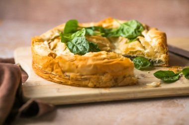 Tahta tahtada ıspanaklı ve peynirli Yunan turtası. Karanlık arka plan. Üst görünüm