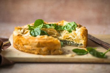 Tahta tahtada ıspanaklı ve peynirli Yunan turtası. Karanlık arka plan. Üst görünüm