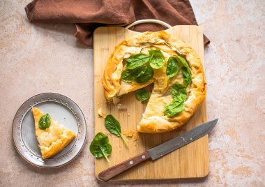 Tahta tahtada ıspanaklı ve peynirli Yunan turtası. Karanlık arka plan. Üst görünüm