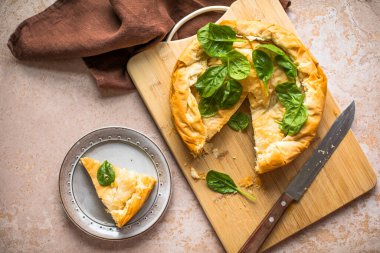Tahta tahtada ıspanaklı ve peynirli Yunan turtası. Karanlık arka plan. Üst görünüm