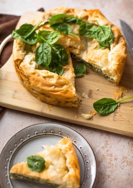 Tahta tahtada ıspanaklı ve peynirli Yunan turtası. Karanlık arka plan. Üst görünüm