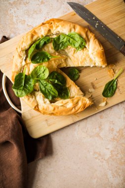 Tahta tahtada ıspanaklı ve peynirli Yunan turtası. Karanlık arka plan. Üst görünüm