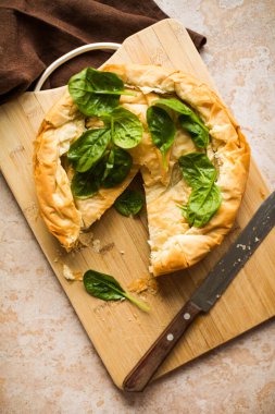 Tahta tahtada ıspanaklı ve peynirli Yunan turtası. Karanlık arka plan. Üst görünüm