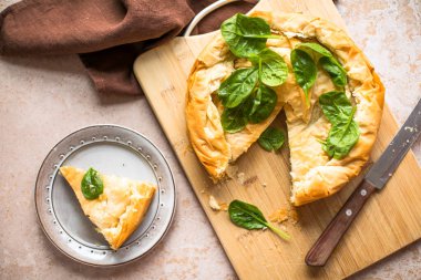 Tahta tahtada ıspanaklı ve peynirli Yunan turtası. Karanlık arka plan. Üst görünüm