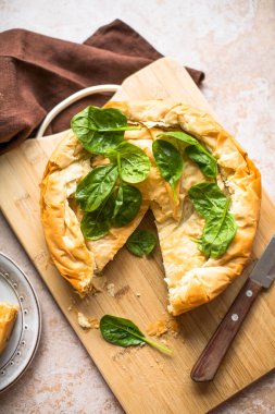 Tahta tahtada ıspanaklı ve peynirli Yunan turtası. Karanlık arka plan. Üst görünüm