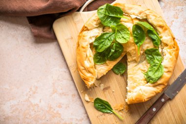 Tahta tahtada ıspanaklı ve peynirli Yunan turtası. Karanlık arka plan. Üst görünüm