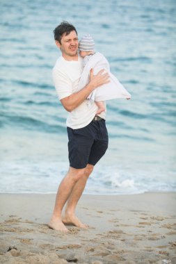 Baba ve çocuk gün batımında tropik plajda oynuyorlar. Deniz tatil beldesinde aile tatili. Babam güneşli bir akşamda çocuklarla okyanus kıyısında oynuyor. Çocuklarla seyahat et. Ebeveyn sevgisi