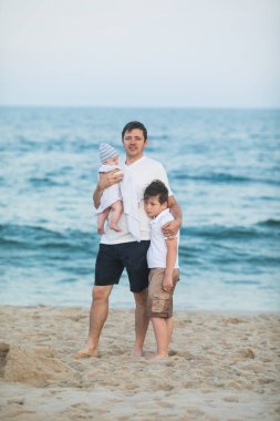 Baba ve çocuk gün batımında tropik plajda oynuyorlar. Deniz tatil beldesinde aile tatili. Babam güneşli bir akşamda çocuklarla okyanus kıyısında oynuyor. Çocuklarla seyahat et. Ebeveyn sevgisi