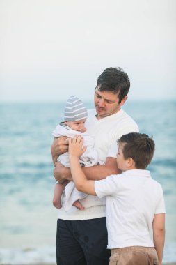 Baba ve çocuk gün batımında tropik plajda oynuyorlar. Deniz tatil beldesinde aile tatili. Babam güneşli bir akşamda çocuklarla okyanus kıyısında oynuyor. Çocuklarla seyahat et. Ebeveyn sevgisi