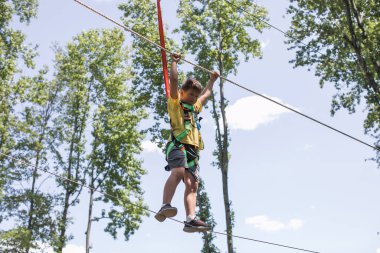 Okullu çocuk zeplin macerasına hazırlanıyor. Dağlara tırmanmak yaz eğlencesidir. Sıcak ve güneşli bir yaz gününde macera parkına tırmanmanın tadını çıkarıyorum. Küçük çocuklar için yaz etkinlikleri. 