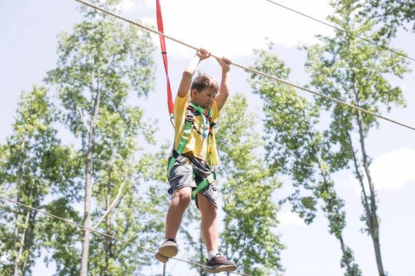 Okullu çocuk zeplin macerasına hazırlanıyor. Dağlara tırmanmak yaz eğlencesidir. Sıcak ve güneşli bir yaz gününde macera parkına tırmanmanın tadını çıkarıyorum. Küçük çocuklar için yaz etkinlikleri. 