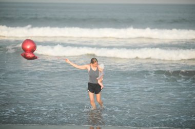 Neşeli genç anne ve küçük oğlu deniz kenarında birlikte eğleniyorlar, baba çocuğu havaya kusuyor.