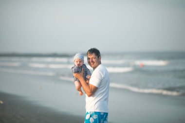 Babalar Günün kutlu olsun. Baba ve bebek kumsalda oynuyorlar. Baba ve çocuk birlikte gün batımının tadını çıkarıyorlar. Sevgi dolu bekar baba, sevimli küçük oğluna sarılıyor..