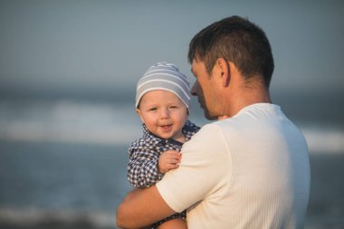 Babalar Günün kutlu olsun. Baba ve bebek kumsalda oynuyorlar. Baba ve çocuk birlikte gün batımının tadını çıkarıyorlar. Sevgi dolu bekar baba, sevimli küçük oğluna sarılıyor..
