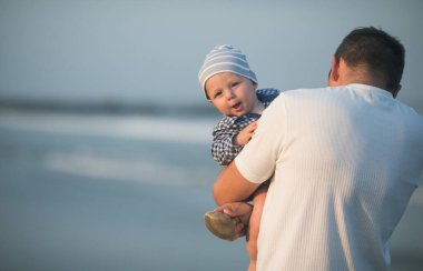 Babalar Günün kutlu olsun. Baba ve bebek kumsalda oynuyorlar. Baba ve çocuk birlikte gün batımının tadını çıkarıyorlar. Sevgi dolu bekar baba, sevimli küçük oğluna sarılıyor..