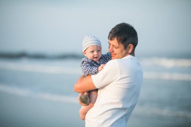 Babalar Günün kutlu olsun. Baba ve bebek kumsalda oynuyorlar. Baba ve çocuk birlikte gün batımının tadını çıkarıyorlar. Sevgi dolu bekar baba, sevimli küçük oğluna sarılıyor..
